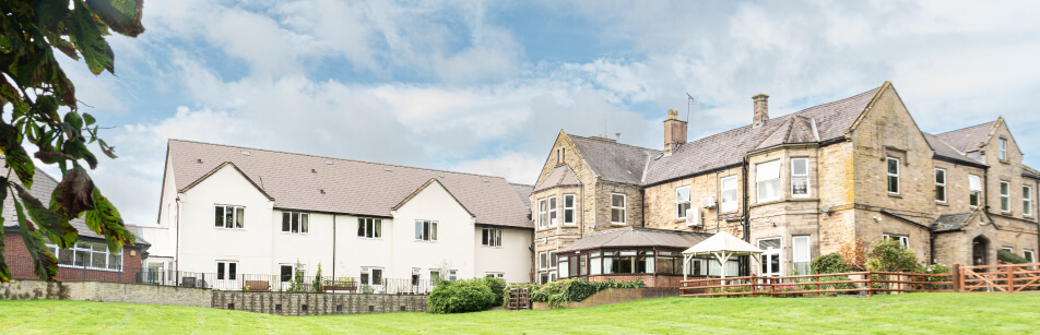 Building with a modern extension connected to a traditional stone listed building under a blue sky