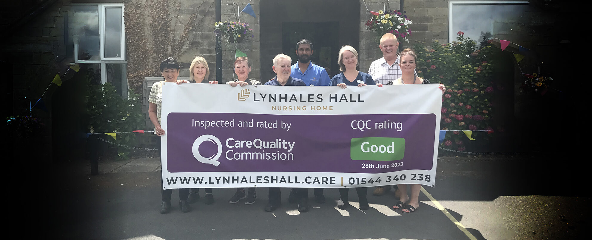 Staff and elderly people  stand together and hold a banner with CQC 'good' rating 