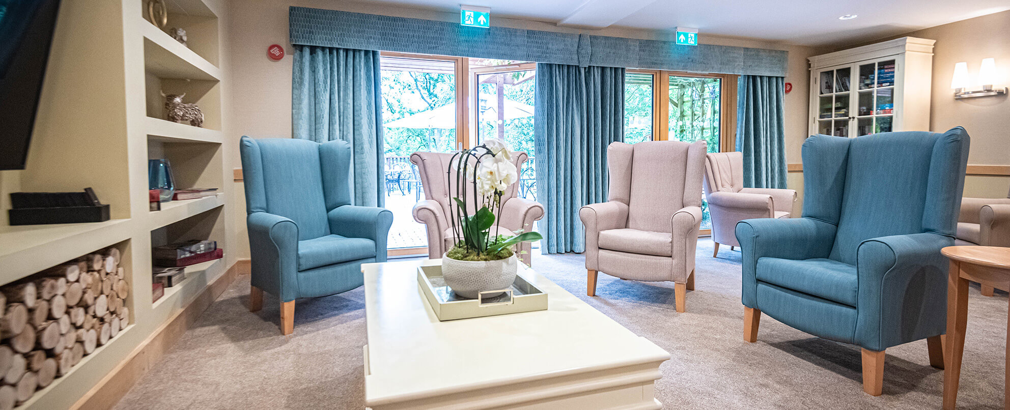 Living room with blue armchairs, a white coffee table, and a view of the outdoors through patio doors