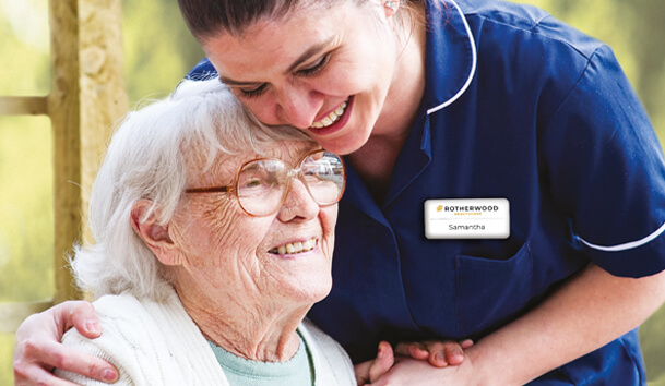 A healthcare worker hugs an older lady