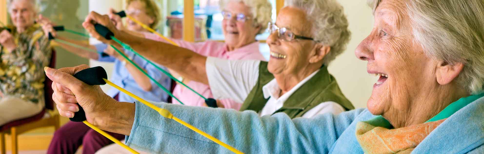 Elderly people take part in an exercise class using resistance bands