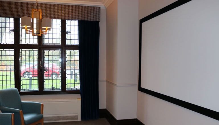 Cinema lounge with a large projection screen with an armchair and a window with a view outside