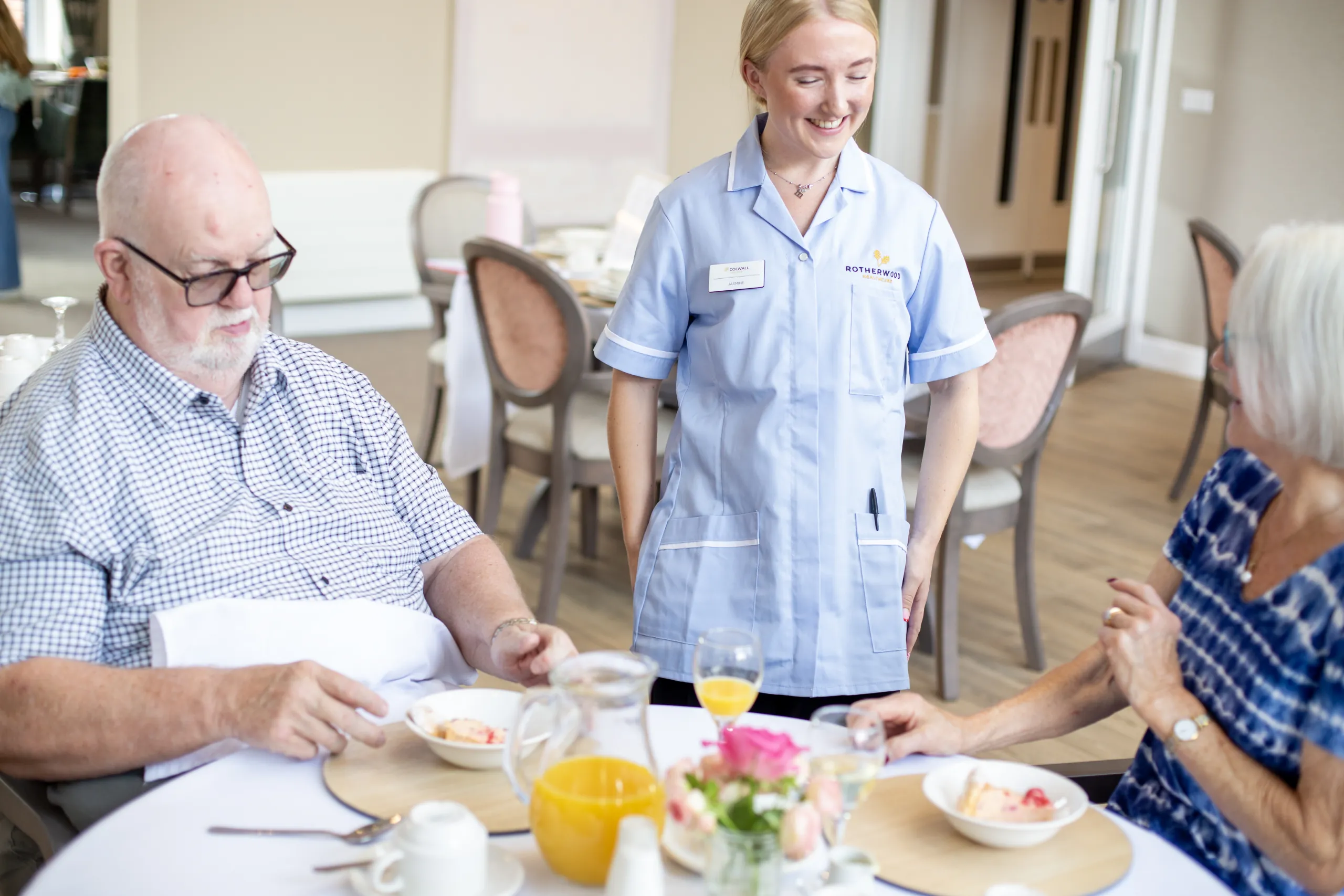 A nurse chatting with residents during breakfast in the Colwall dining room