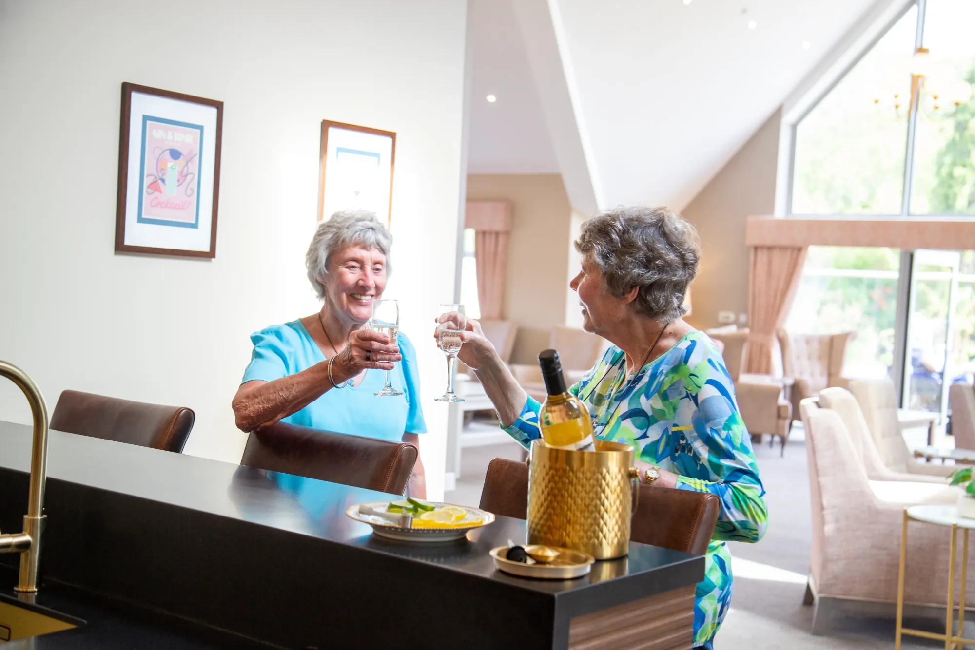 Two residents raising a toast with drinks at the bar in Colwall Care Home