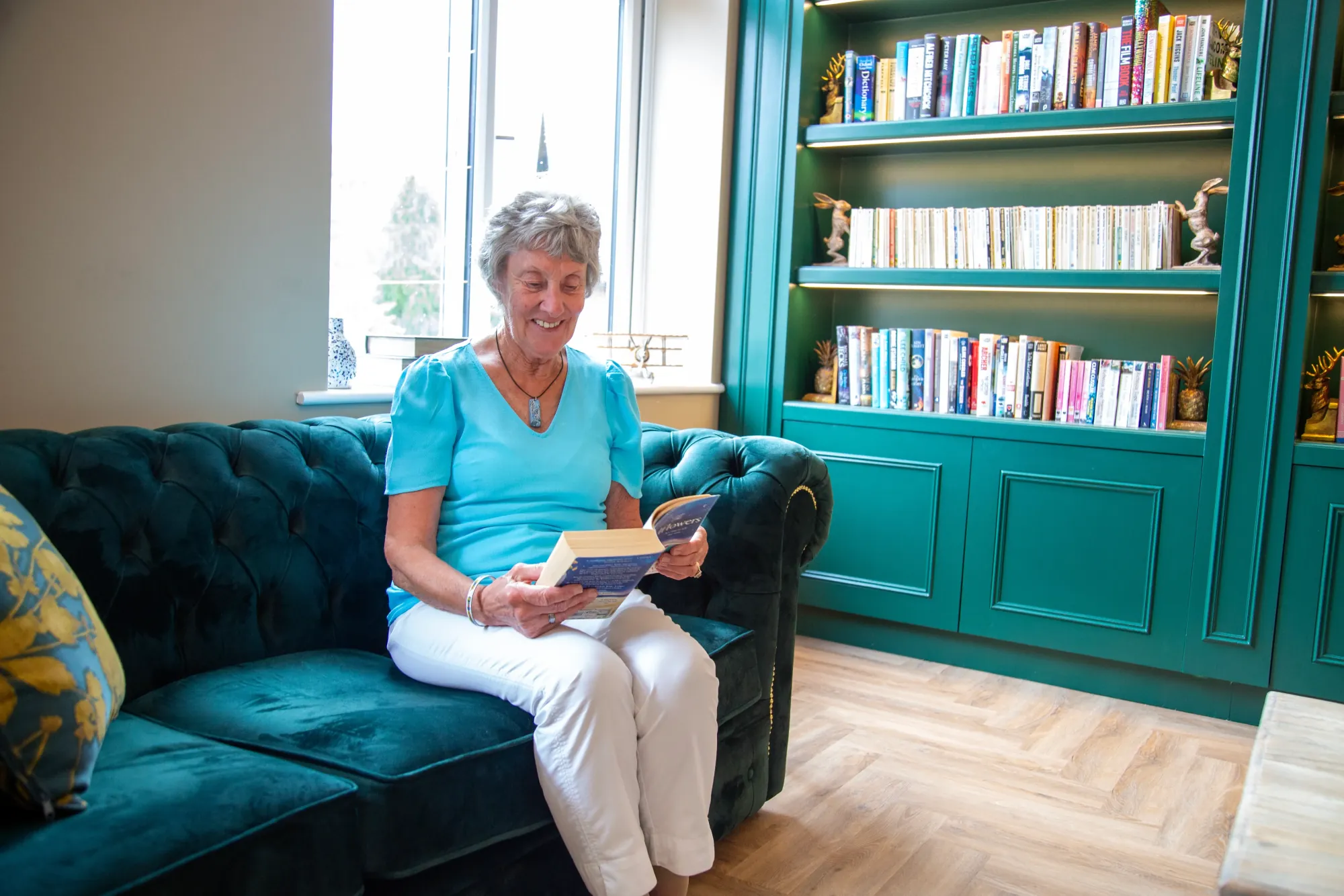A resident reading a book on a sofa in the Colwall library