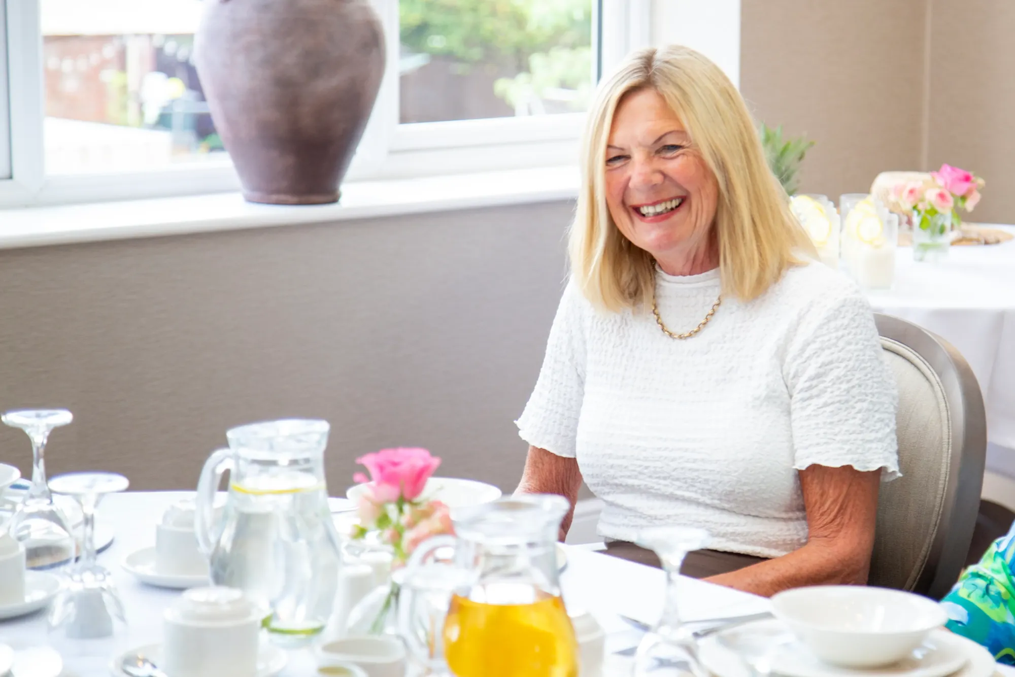 A smiling resident seated at a laid table in the Colwall dining room