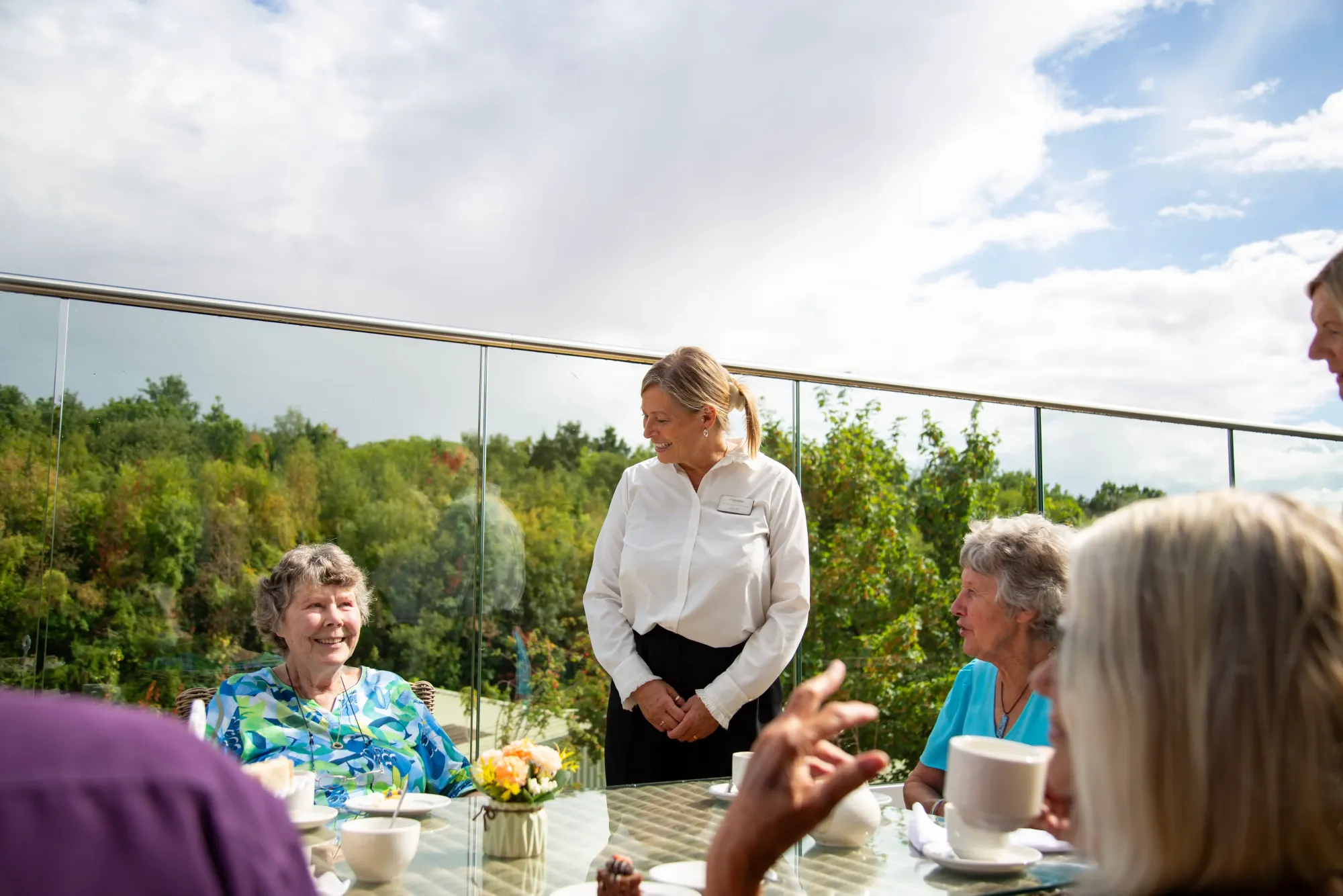 A member of the Colwall team chatting with residents over tea on the terrace, overlooking the surrounding countryside