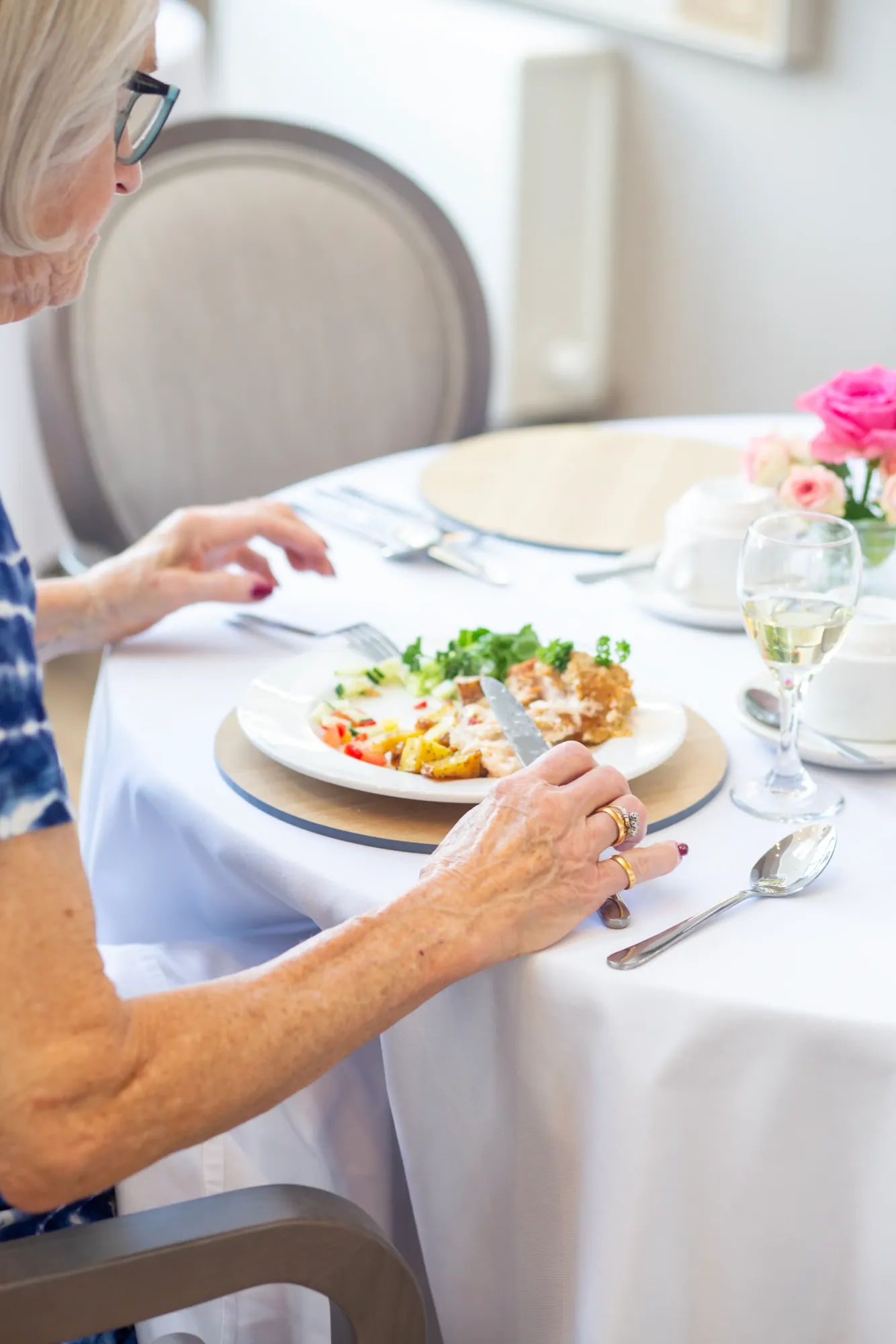 A resident enjoying lunch at a table laid with fresh flowers in the Colwall dining room