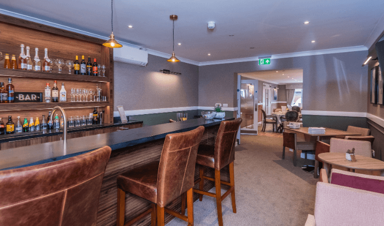 A lady with green trousers having her foot treated by another lady in an apron