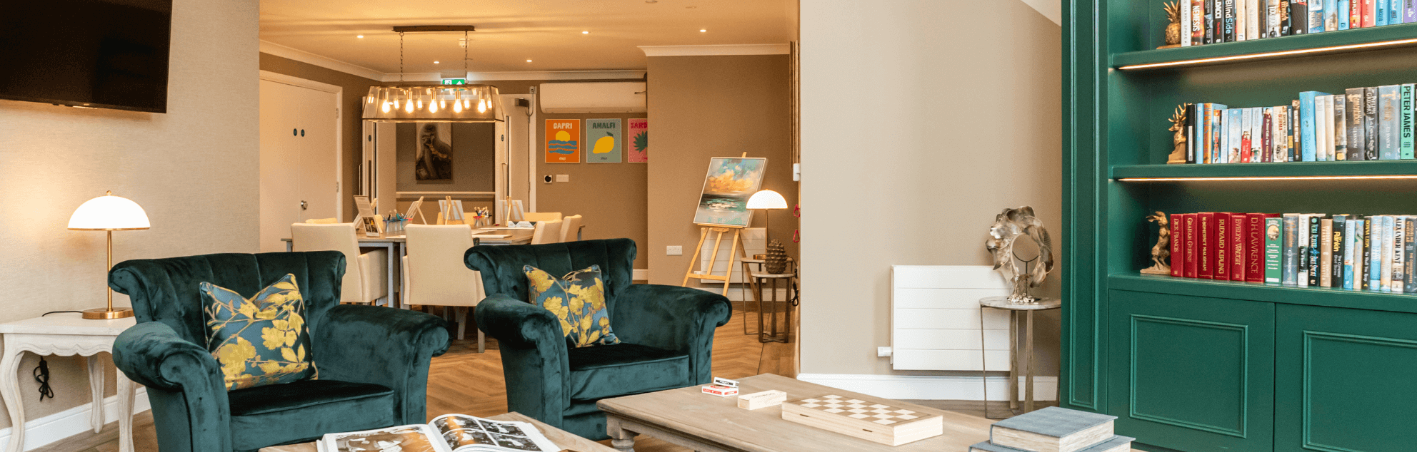 Inviting communal room with velvet green chairs and emerald, green bookcase