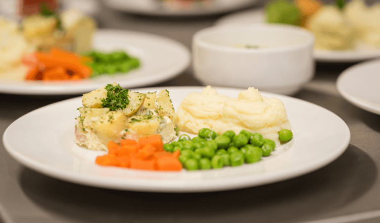 A large dining room with tables laid with napkins, plates and cutlery.