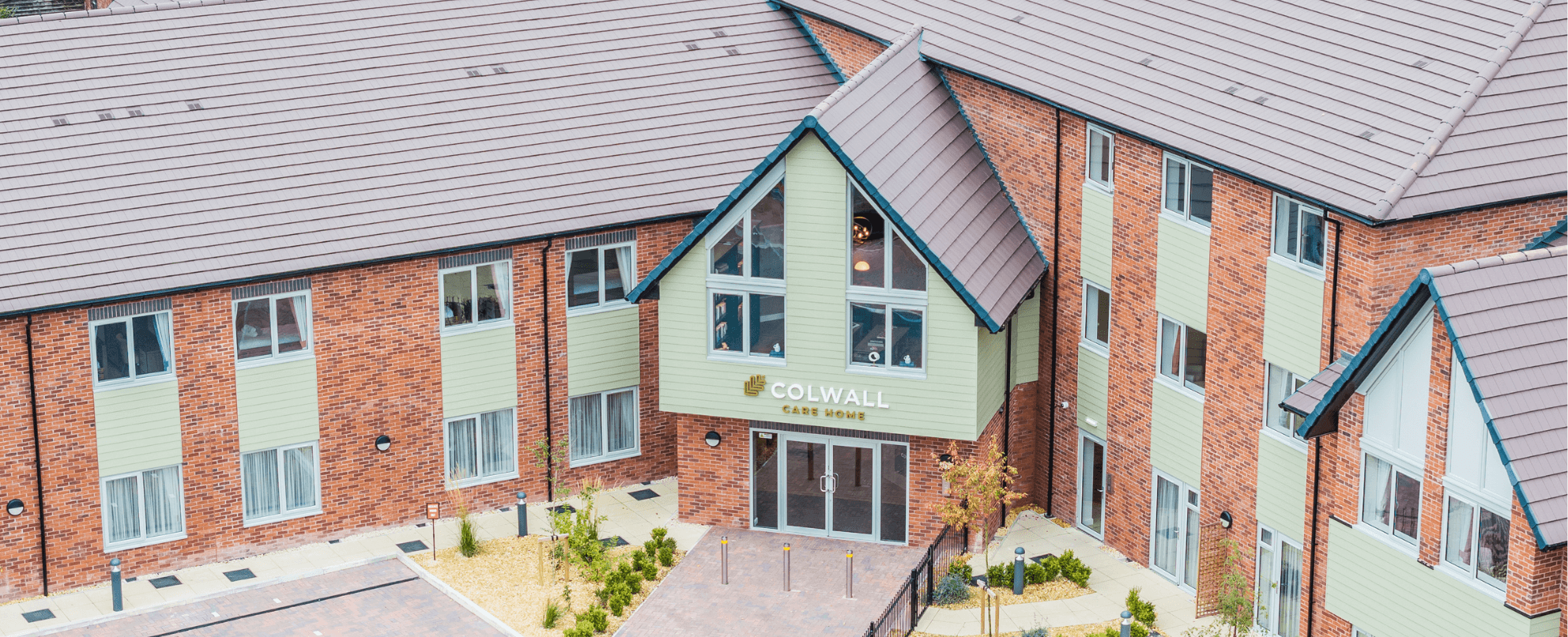 View from above of red brick and green render building with balcony