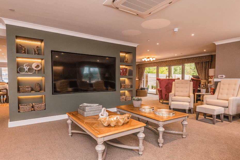 A large built in television with decorative shelves either side, laid coffee tables and relaxed seating 