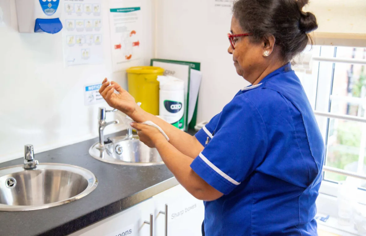 A Dorset House nurse washing her hands at the clinical sink