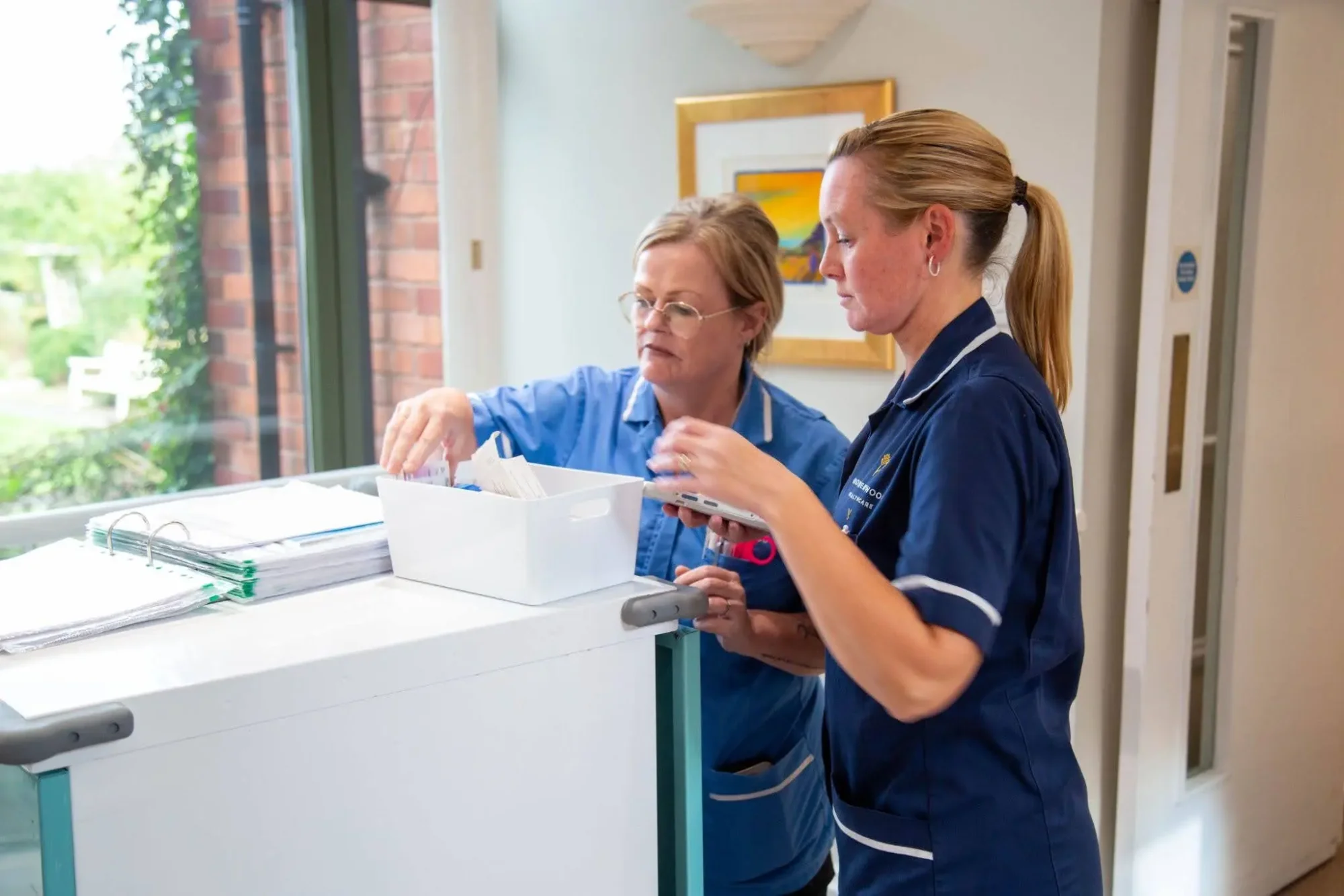 Two Dorset House nurses checking medication together at the treatment trolley