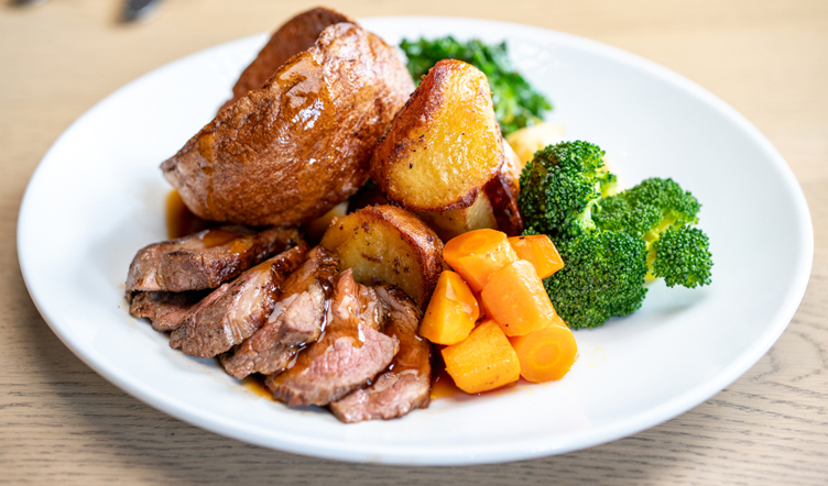 Plate of beef dinner with potatoes, vegetables and a Yorkshire pudding