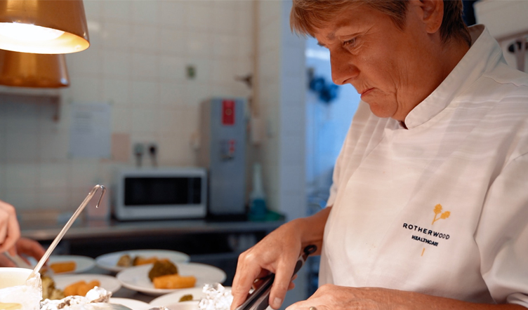 Female Chef in Chef whites  dishes out a meal