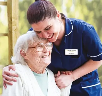 A healthcare worker hugs an older lady