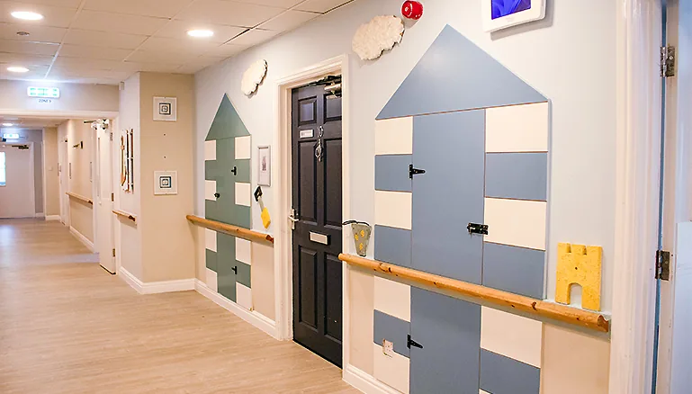 A corridor with blue carpeting and walls painted in light blue and white
