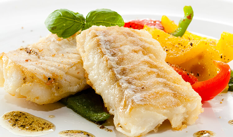 Grilled fish fillets, served with colourful bell pepper slices and a sprinkle of herbs on a white plate