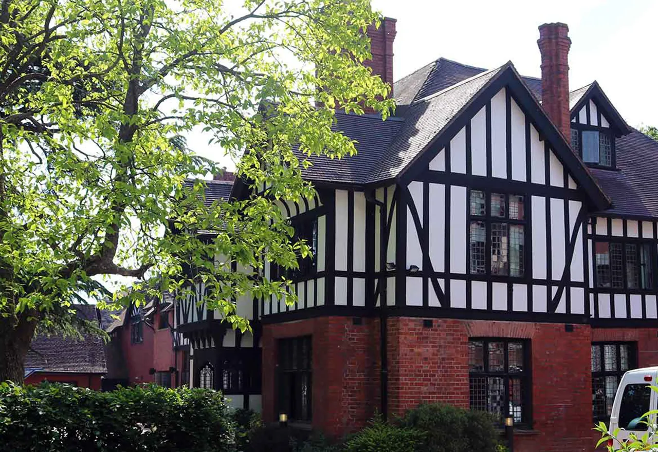 The black and white Tudor-style frontage of Hampton Grange, framed by a mature tree