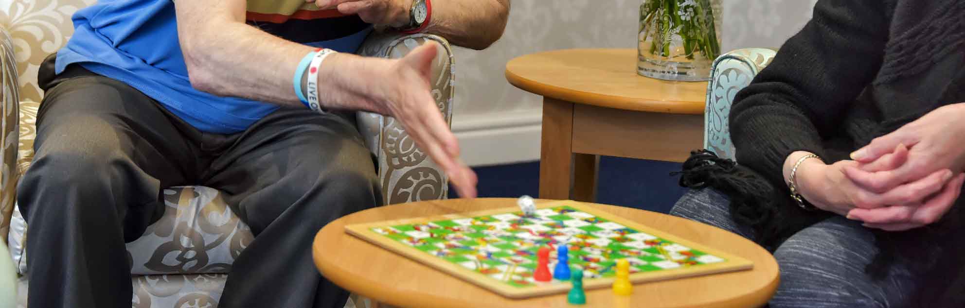 People seated around a table, playing a board game  with colourful pieces.