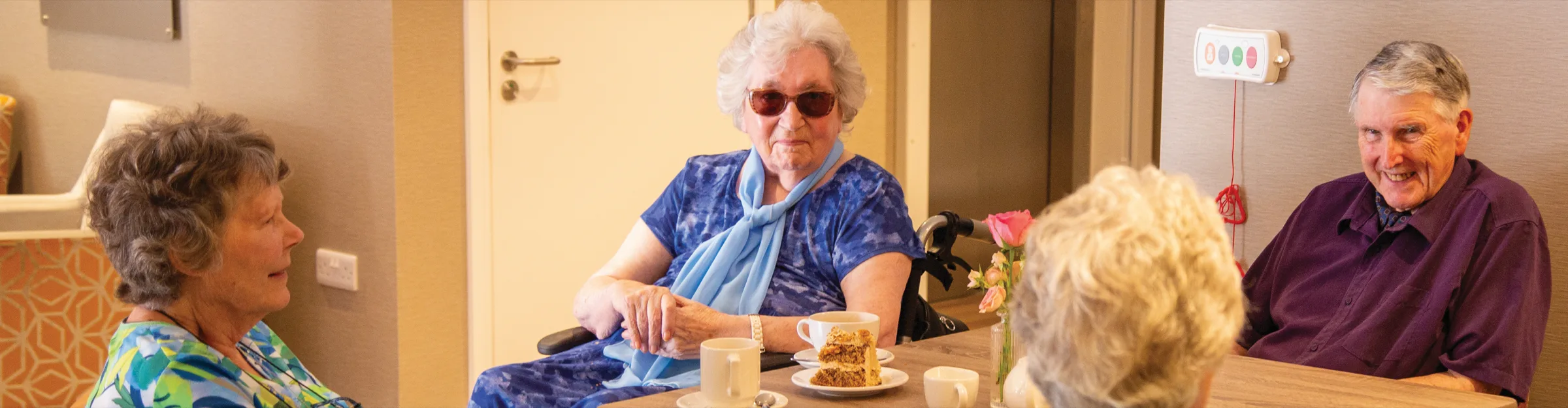 Residents at Colwall chatting around a table over cups of tea and cake