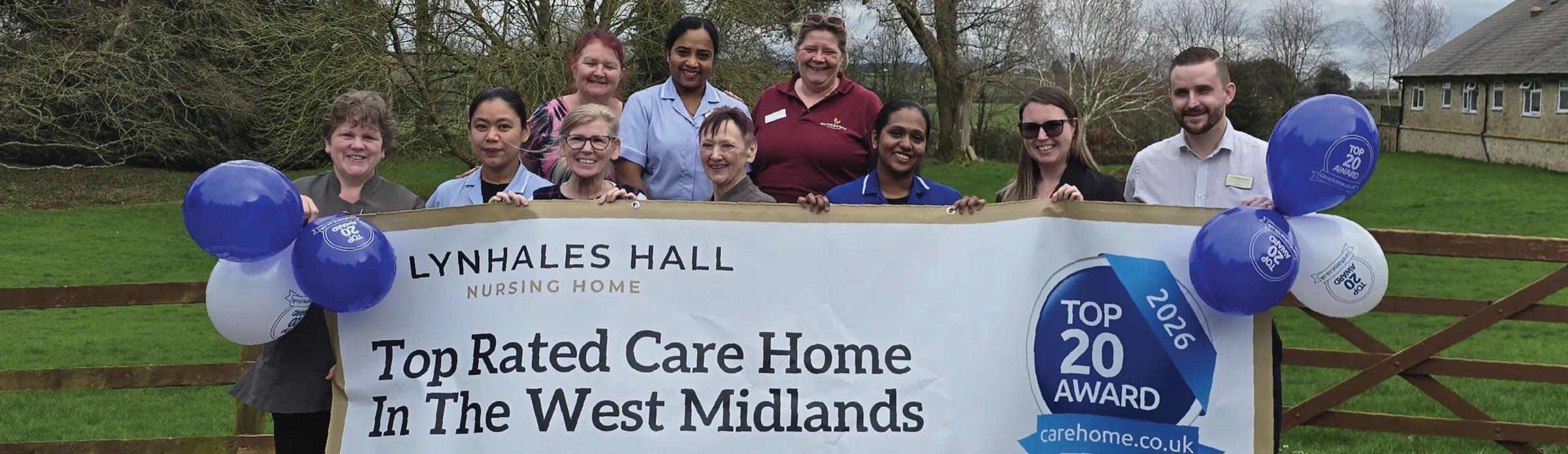 The Lynhales Hall team holding a banner celebrating their carehome.co.uk Top 20 award as a top rated care home in the West Midlands