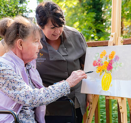 A lifestyle coordinator supports a resident to do art outside