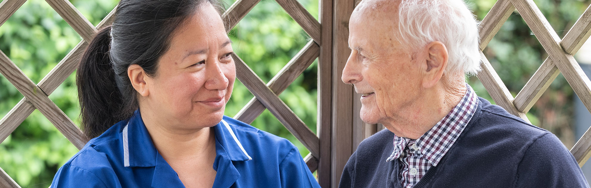 A nurse and an elderly man smiling at each other