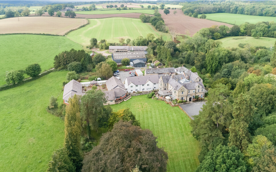 Aerial view of a countryside estate with buildings and green fields