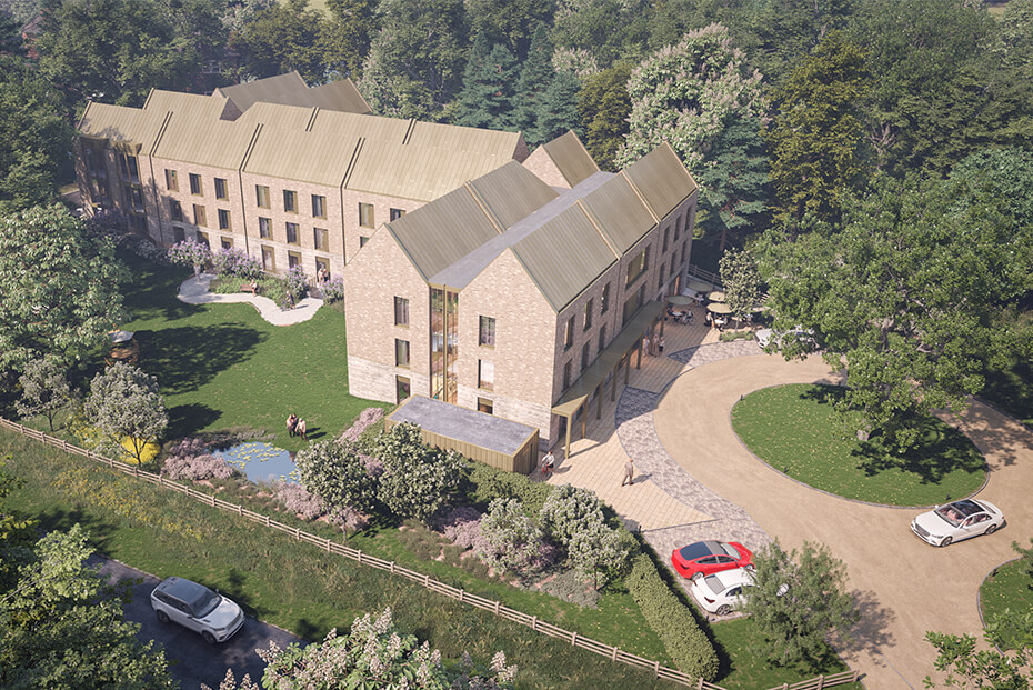 Aerial view of a large, multi-winged building with gabled roofs, surrounded by lush greenery and trees