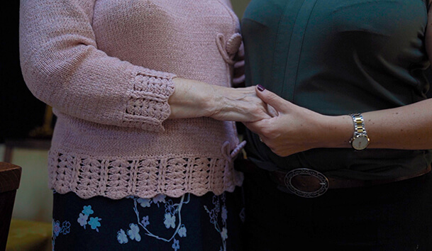 Close up of resident and staff member holding hands