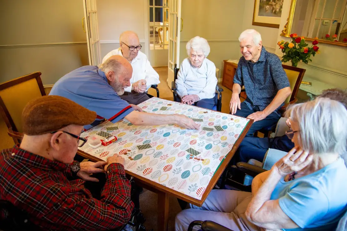 A group of Dorset House residents gathered around a table playing a board game together