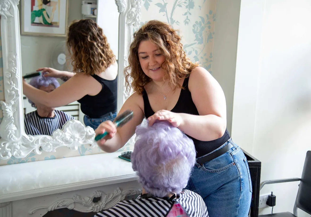 A hairdresser styling a resident's hair in the Dorset House salon