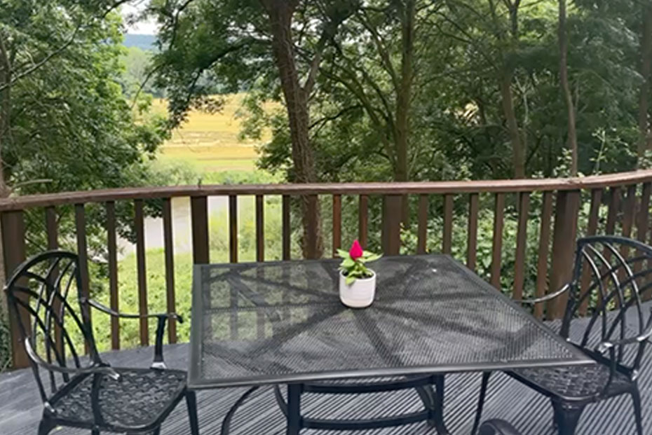 A wooden bench on a deck, surrounded by trees, overlooking a river