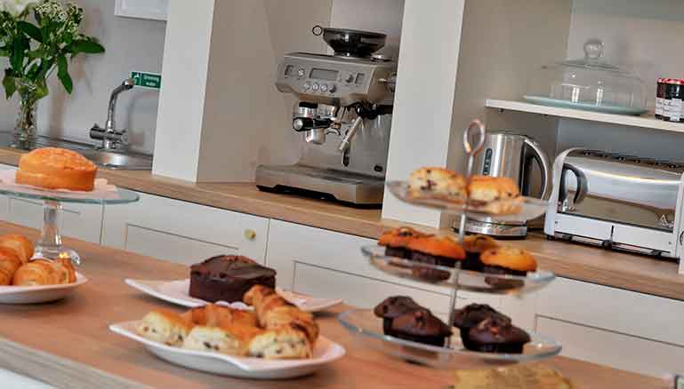 A kitchen counter with a variety of baked goods displayed, including croissants, muffins, and a cake. 