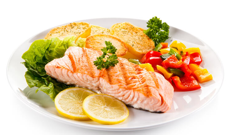 A plate of grilled salmon with lemon slices, a side of mixed vegetables, and roasted potatoes garnished with parsley