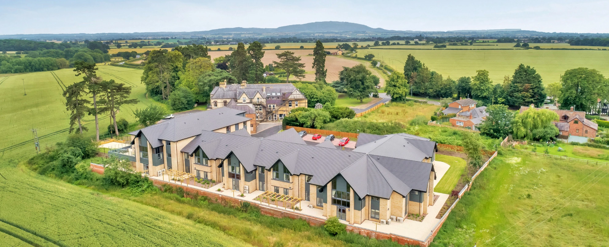 An aerial view of Roden Hall Care Home and its original manor house, surrounded by open Shropshire farmland with the Wrekin on the horizon