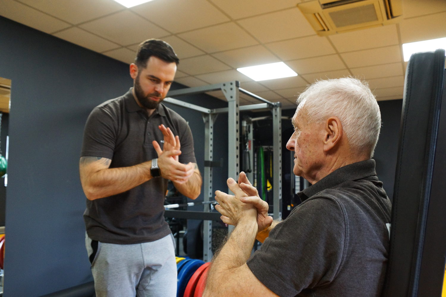 Instructor leading elderly man doing isometric training