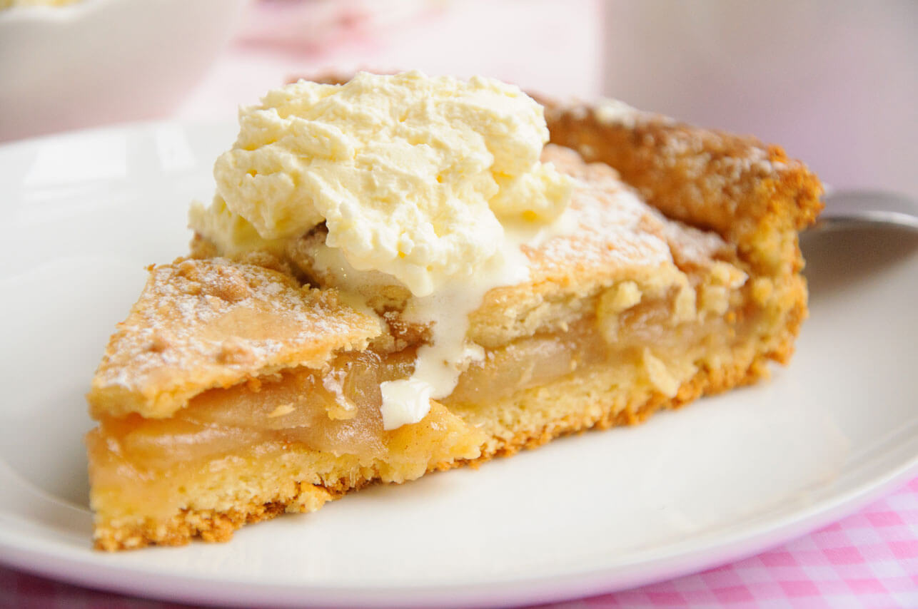 A slice of apple pie topped with ice cream on a white plate