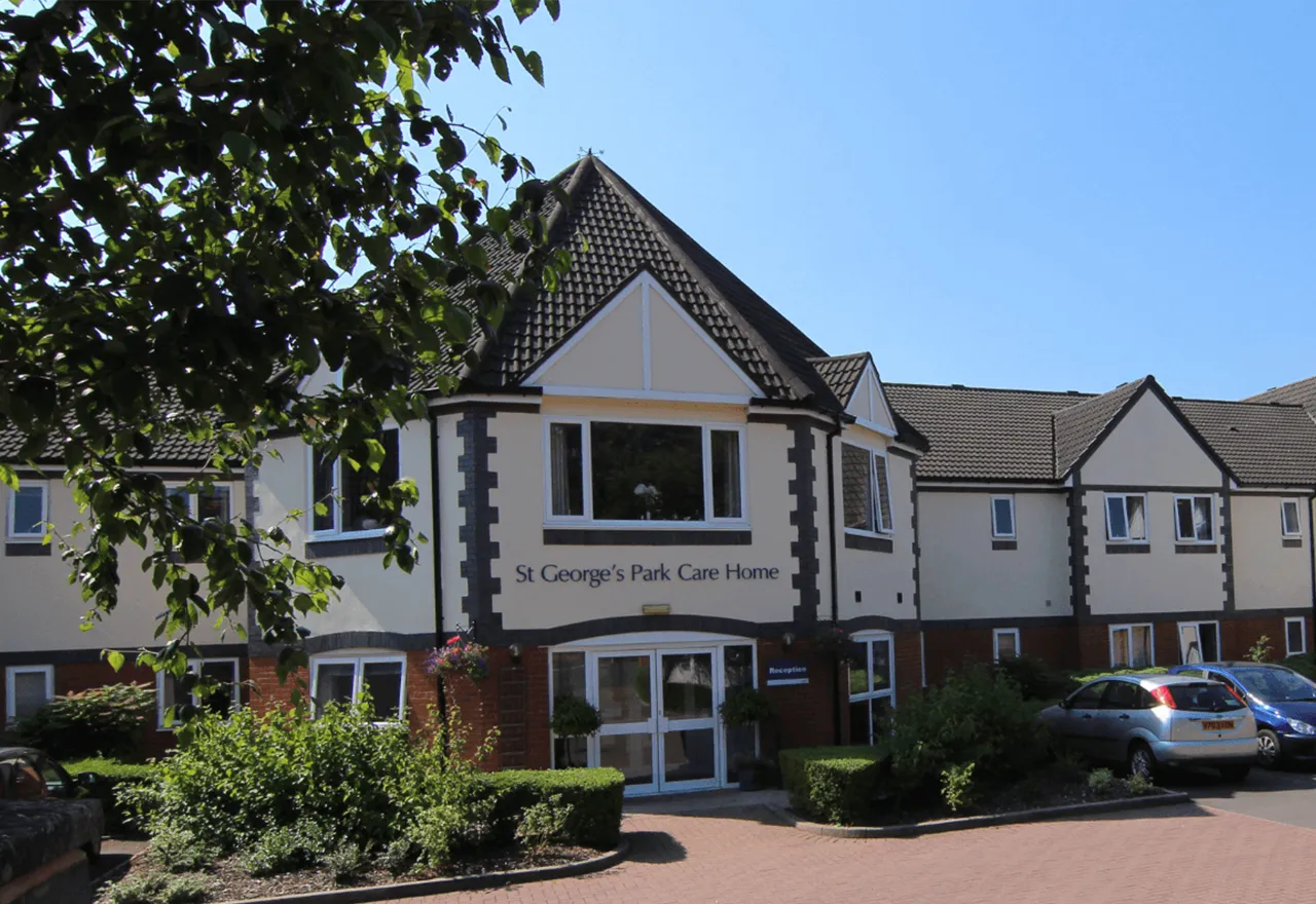 The front entrance of St George’s Park Care Home, with cream render, dark timber detailing and a bay window