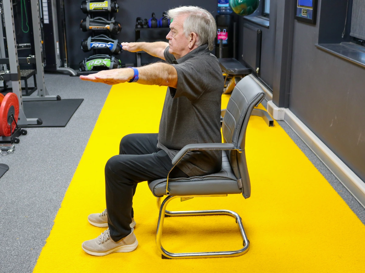 An elderly man taking part in a seated exercise class in the gym